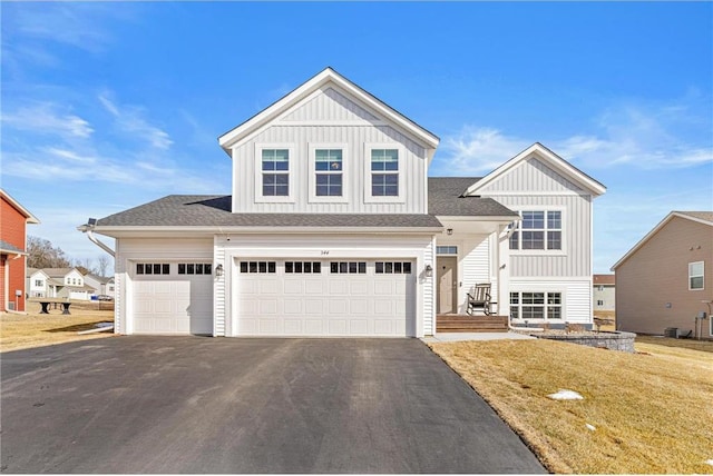 view of front of property with aphalt driveway, an attached garage, board and batten siding, and a front yard