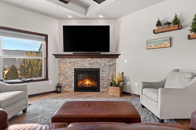 living area with a fireplace, wood finished floors, and baseboards