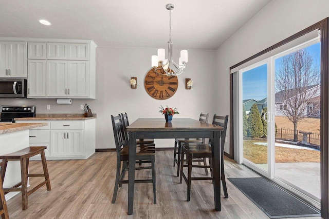 dining space featuring a notable chandelier, light wood-style flooring, and baseboards