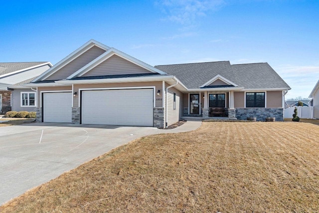 craftsman-style home featuring driveway, stone siding, fence, an attached garage, and a front yard