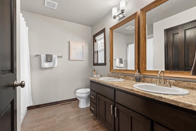 full bathroom with toilet, wood finished floors, visible vents, and a sink