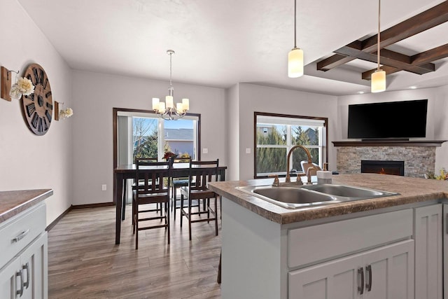 kitchen with a sink, light wood-style floors, coffered ceiling, and a healthy amount of sunlight