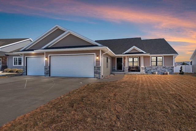 craftsman-style home featuring driveway, fence, a garage, and stone siding