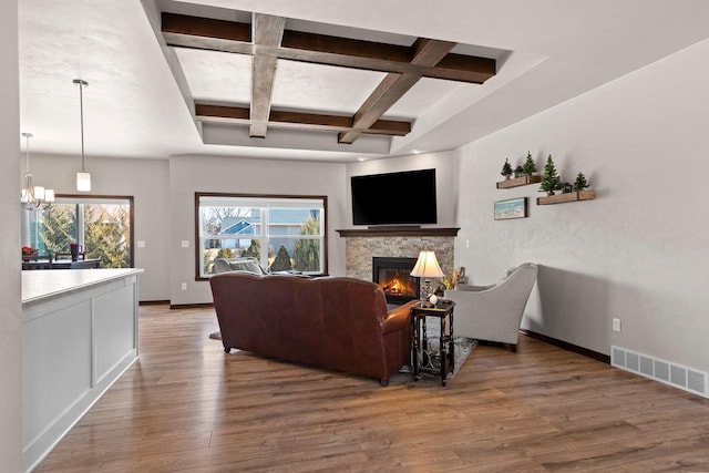 living room featuring visible vents, coffered ceiling, a glass covered fireplace, wood-type flooring, and baseboards