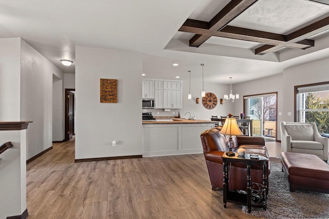 living room featuring a notable chandelier, baseboards, light wood-style floors, and coffered ceiling