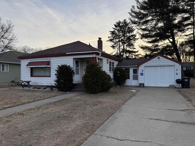 view of front facade with concrete driveway, a garage, and a chimney