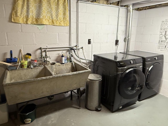 washroom featuring a sink, washing machine and dryer, and laundry area