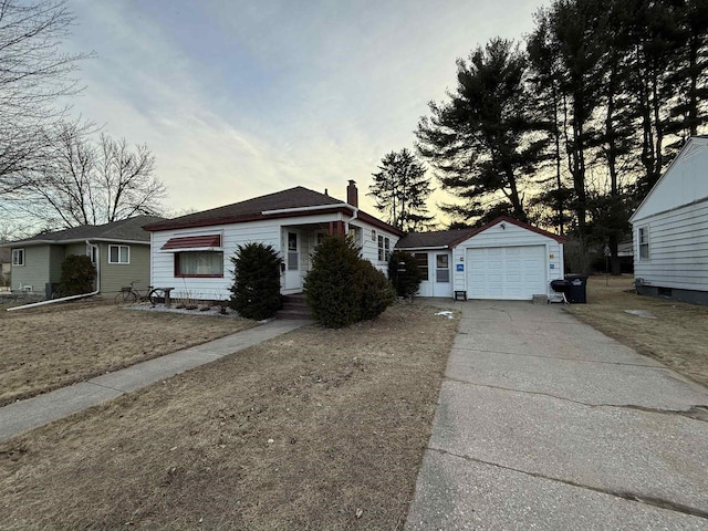 view of front facade featuring an outbuilding, a detached garage, driveway, and a chimney