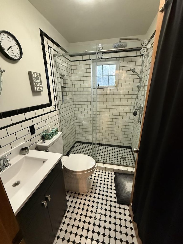 full bathroom with a shower stall, vanity, toilet, and tile walls