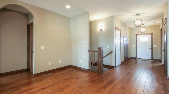 entryway with arched walkways, visible vents, baseboards, and hardwood / wood-style flooring