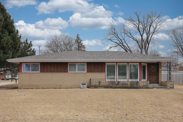 ranch-style home with brick siding, a chimney, roof with shingles, and fence