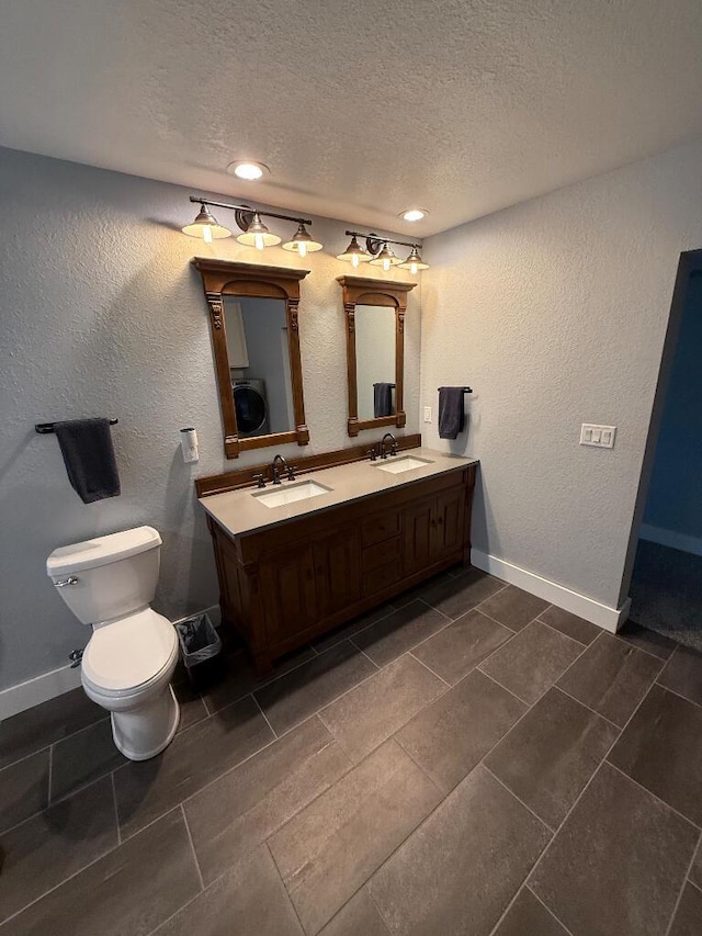 full bathroom featuring a sink, washer / clothes dryer, a textured ceiling, and a textured wall