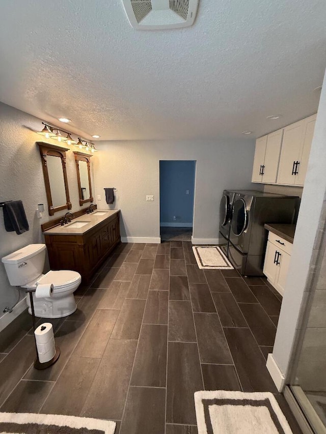 bathroom with washer and dryer, wood finish floors, visible vents, and a sink