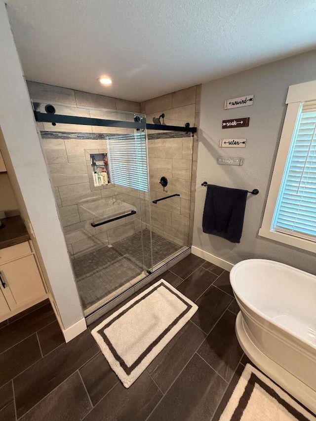 full bath with baseboards, a soaking tub, a stall shower, and a textured ceiling