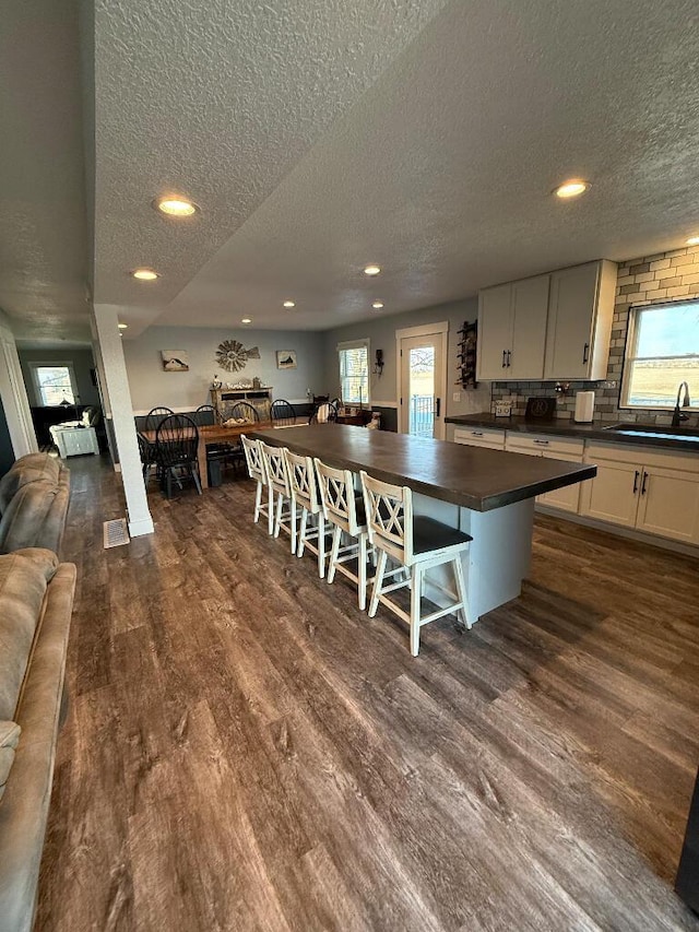 kitchen with dark wood finished floors, dark countertops, open floor plan, and a sink