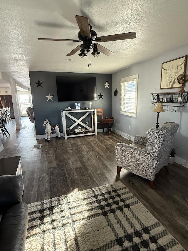 living area with a healthy amount of sunlight, a textured ceiling, baseboards, and wood finished floors