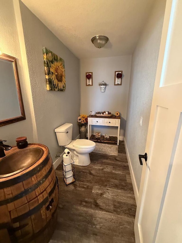 bathroom featuring toilet, vanity, baseboards, and wood finished floors