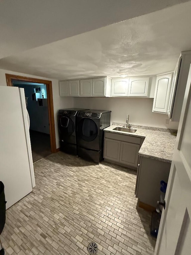 clothes washing area featuring a sink, cabinet space, and washer and dryer