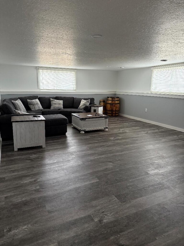 unfurnished living room with baseboards, a textured ceiling, a healthy amount of sunlight, and dark wood-style floors