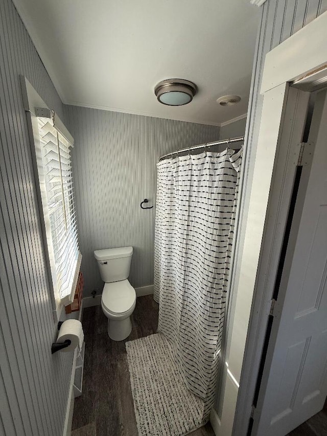 bathroom with ornamental molding, toilet, a shower with curtain, and wood finished floors