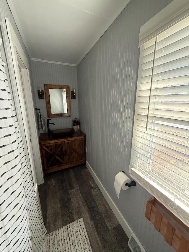 bathroom featuring vanity, wood finished floors, baseboards, and ornamental molding