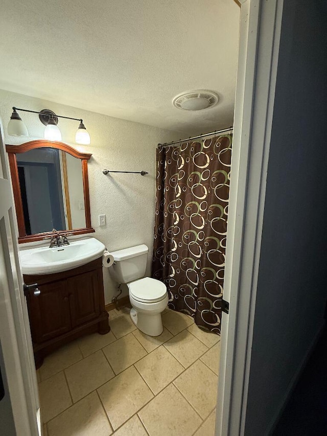 bathroom with tile patterned flooring, visible vents, toilet, a textured wall, and vanity