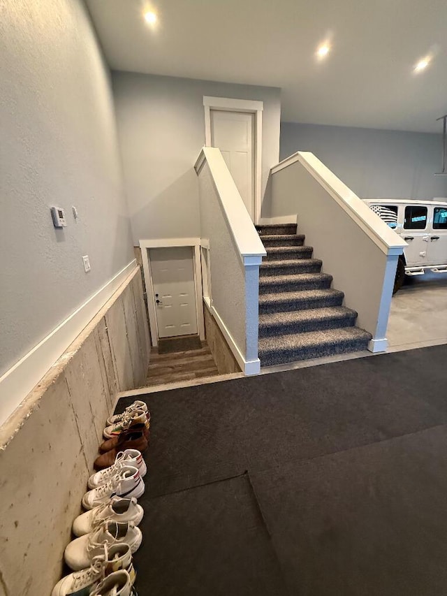 stairway with a wainscoted wall and recessed lighting