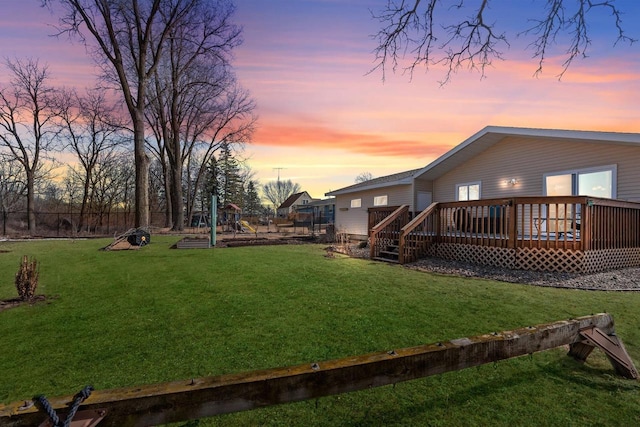 yard at dusk featuring a deck and fence