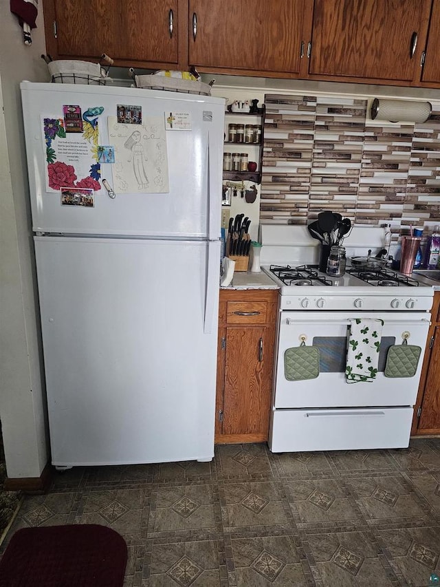 kitchen with brown cabinets, white appliances, light countertops, and dark floors