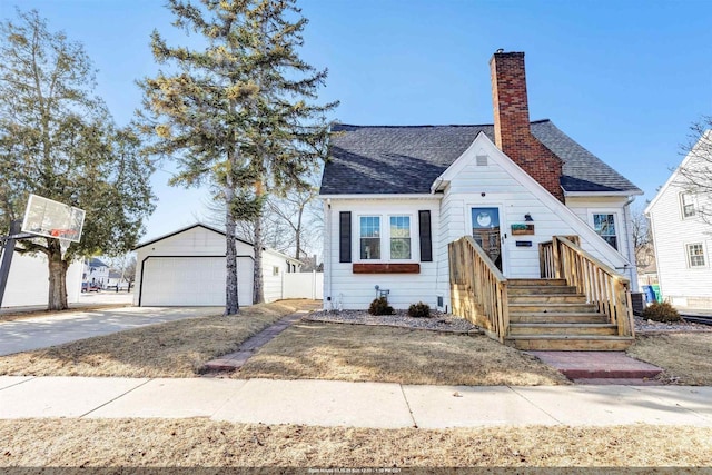 view of front of house with a chimney, a detached garage, an outdoor structure, and a shingled roof