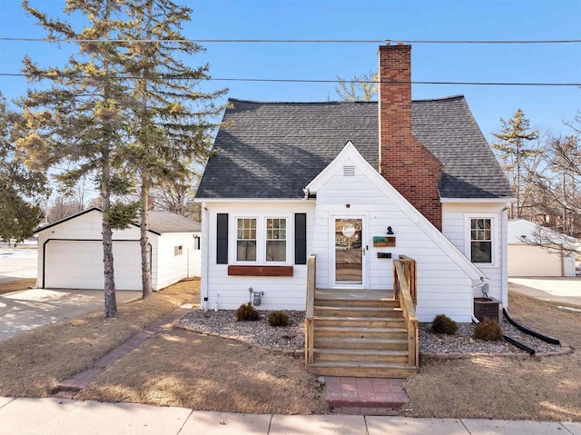 view of front of home featuring central AC, roof with shingles, an outdoor structure, a garage, and a chimney