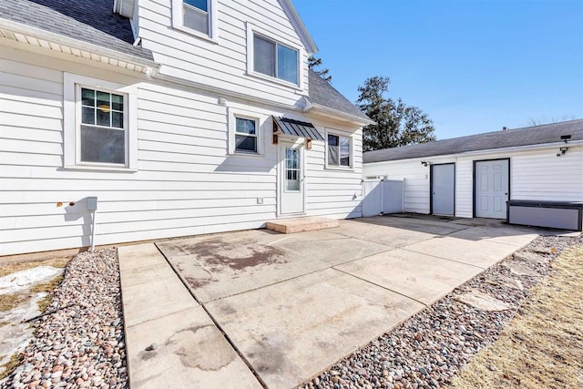 rear view of house featuring roof with shingles and a patio area