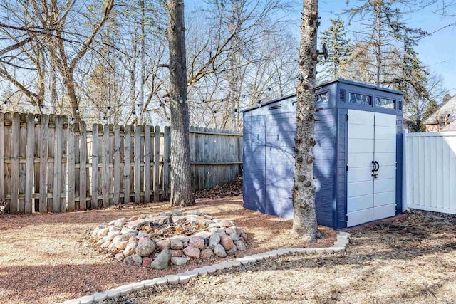 view of shed featuring a fenced backyard and an outdoor fire pit