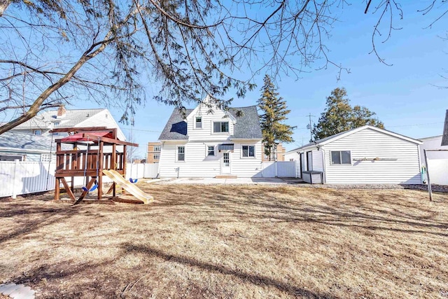 rear view of property featuring fence, a shingled roof, entry steps, and a playground