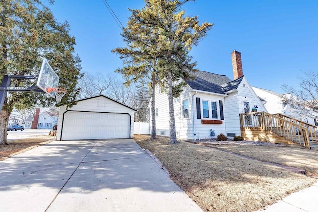 view of front of house featuring a chimney, a detached garage, an outdoor structure, and a shingled roof