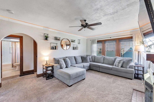 living area featuring ornamental molding, a ceiling fan, a textured ceiling, arched walkways, and carpet flooring