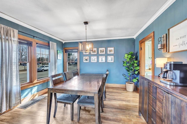 dining space featuring visible vents, a notable chandelier, wood finished floors, and crown molding