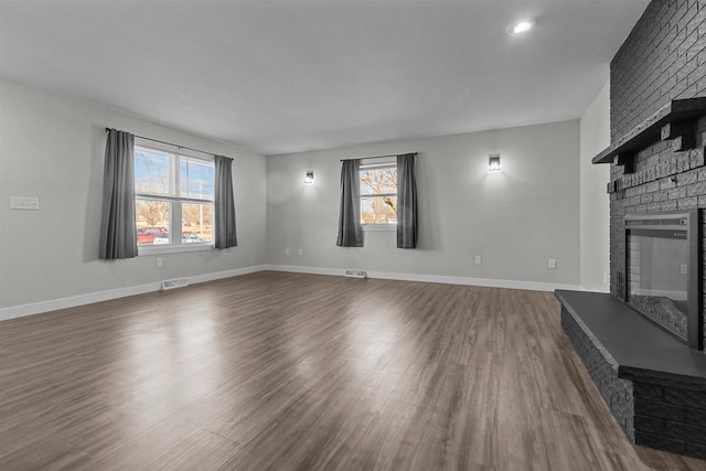 unfurnished living room with baseboards, visible vents, dark wood finished floors, recessed lighting, and a brick fireplace