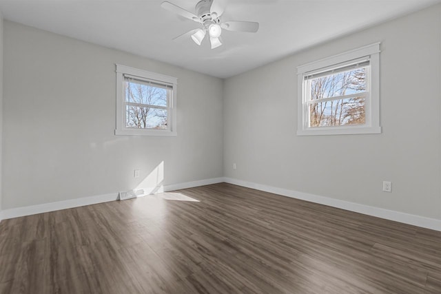 spare room with a ceiling fan, wood finished floors, baseboards, and a wealth of natural light