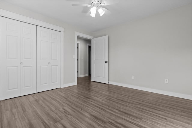 unfurnished bedroom with a closet, baseboards, wood finished floors, and a ceiling fan