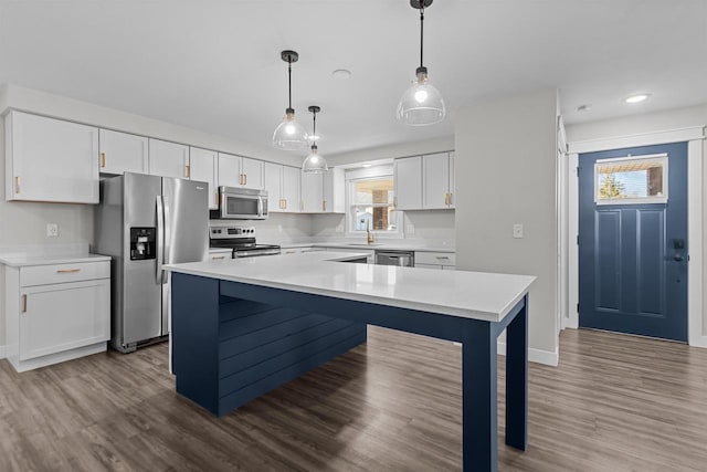 kitchen with a sink, dark wood-style floors, white cabinetry, appliances with stainless steel finishes, and light countertops