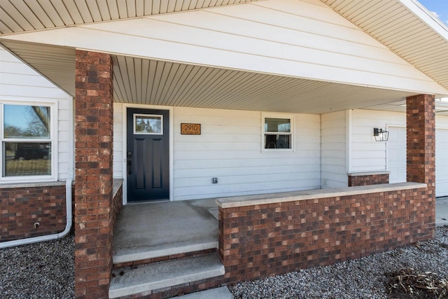 property entrance with brick siding and a porch