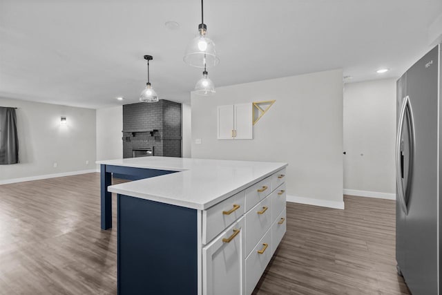 kitchen featuring a brick fireplace, open floor plan, freestanding refrigerator, white cabinets, and dark wood-style flooring