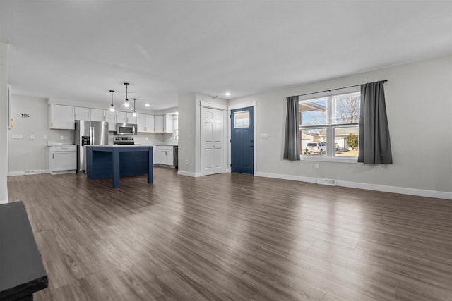 unfurnished living room with visible vents, baseboards, and dark wood-style flooring