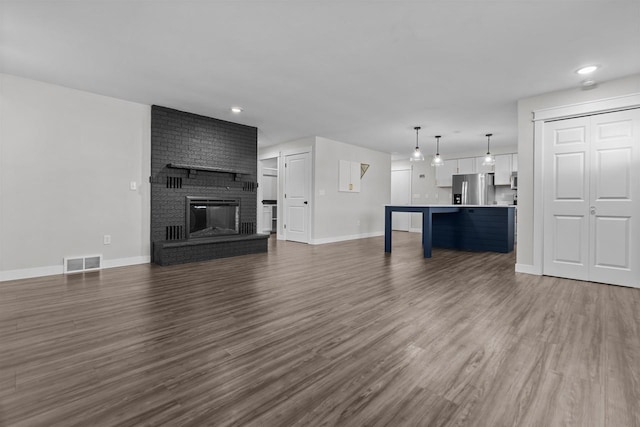 unfurnished living room featuring visible vents, baseboards, recessed lighting, a fireplace, and dark wood-style flooring