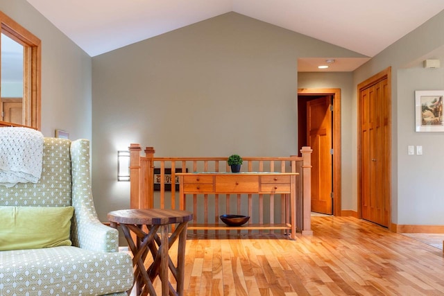 living area with baseboards, light wood-style floors, and lofted ceiling