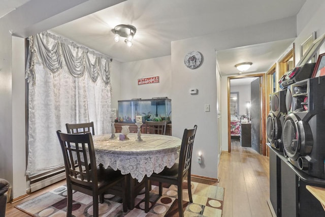 dining room with baseboards, light wood-type flooring, and baseboard heating