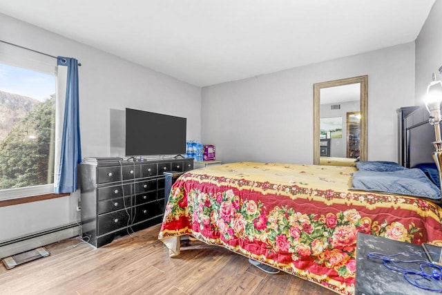 bedroom with visible vents, wood finished floors, and a baseboard radiator