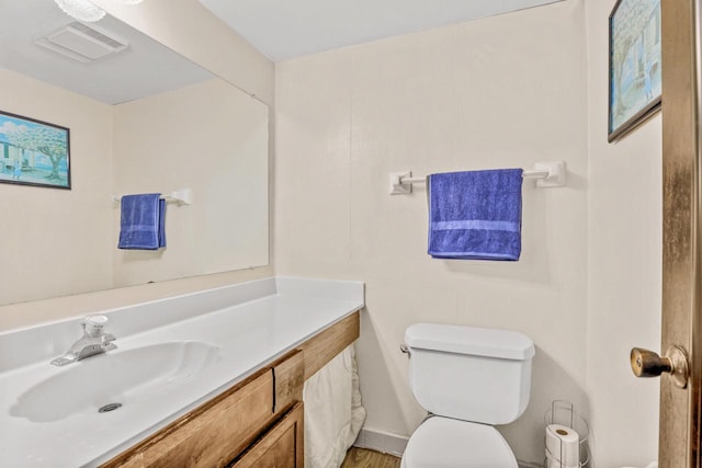 half bathroom featuring visible vents, toilet, and vanity