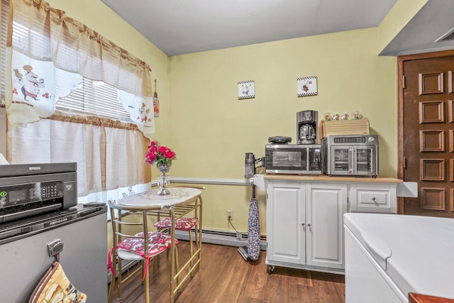 kitchen featuring dark wood finished floors, light countertops, white cabinetry, stainless steel microwave, and a baseboard heating unit